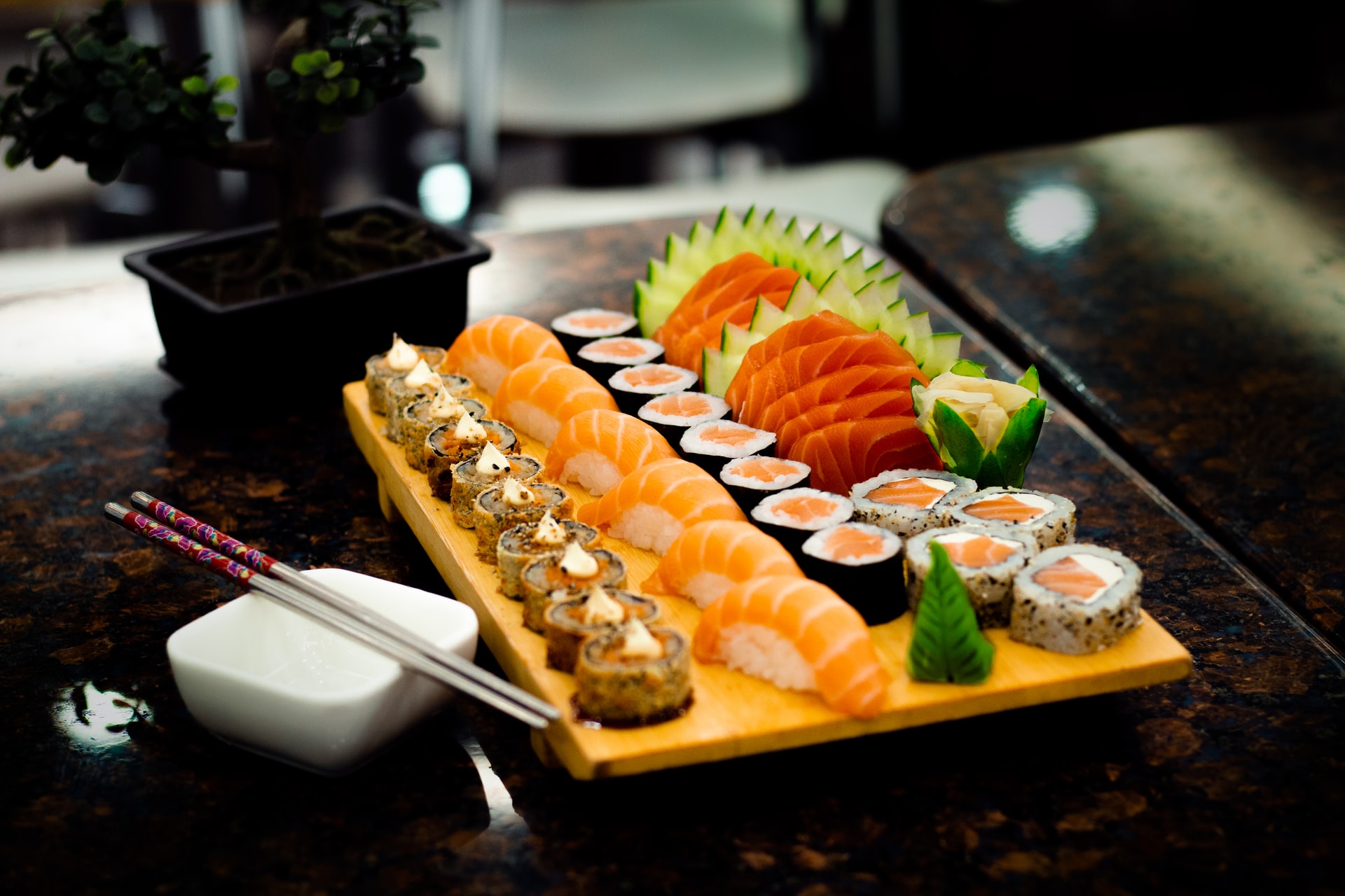 picture of several rows of sushi laid out on a wooden slab, including sushi rolls and other shapes.
